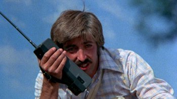 Movie still from “The Hills Have Eyes” (1977), directed by Wes Craven – A man holding a video camera up to his face; Close Up shot, Low angle