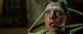 Movie still from “The Hitchhiker's Guide to the Galaxy” (2005), directed by Garth Jennings – A man with a taped up face looking at the camera; Close Up shot, Overhead angle