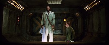 Movie still from “The Hitchhiker's Guide to the Galaxy” (2005), directed by Garth Jennings – A man standing next to a boy on a stage; Medium shot, Low angle