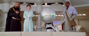 Movie still from “The Hitchhiker's Guide to the Galaxy” (2005), directed by Garth Jennings – A woman standing next to a robot in a room; Medium shot, Low angle