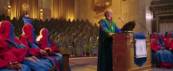 Movie still from “The Hitchhiker's Guide to the Galaxy” (2005), directed by Garth Jennings – A man in a green and blue robe giving a speech; Wide shot, High angle