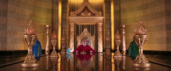 Movie still from “The Hitchhiker's Guide to the Galaxy” (2005), directed by Garth Jennings – A man sitting at a table in front of an ornate room; Wide shot, Low angle