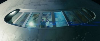 Movie still from “The Hitchhiker's Guide to the Galaxy” (2005), directed by Garth Jennings – A man and a woman are standing in a window; Wide shot, Overhead angle