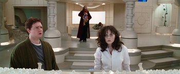 Movie still from “The Hitchhiker's Guide to the Galaxy” (2005), directed by Garth Jennings – A woman sitting in front of a staircase in a room; Medium shot, Over the shoulder angle