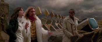 Movie still from “The Hitchhiker's Guide to the Galaxy” (2005), directed by Garth Jennings – Two men are standing in front of a row of golden statues; Medium shot, Over the shoulder angle