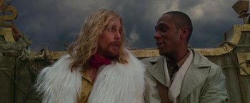 Movie still from “The Hitchhiker's Guide to the Galaxy” (2005), directed by Garth Jennings – A man with long blonde hair standing next to another man; Close Up shot, Low angle