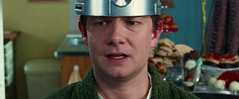 Movie still from “The Hitchhiker's Guide to the Galaxy” (2005), directed by Garth Jennings – A man wearing a helmet with a bunch of food in the background; Close Up shot, High angle