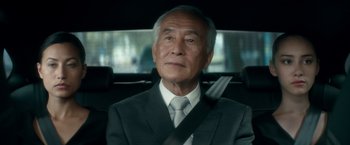 Movie still from “The Hitman's Bodyguard” (2017), directed by Patrick Hughes – An older man sitting in the back seat of a car; Close Up shot, Over the shoulder angle