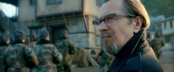 Movie still from “The Hitman's Bodyguard” (2017), directed by Patrick Hughes – A person wearing glasses with a building in the background; Close Up shot, Over the shoulder angle