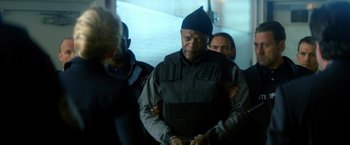 Movie still from “The Hitman's Bodyguard” (2017), directed by Patrick Hughes – A man in a black jacket is being held down by a group of people; Medium shot, Over the shoulder angle