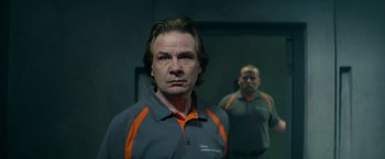 Movie still from “The Hitman's Bodyguard” (2017), directed by Patrick Hughes – A man in a gray and orange shirt standing in front of a mirror; Close Up shot, Low angle