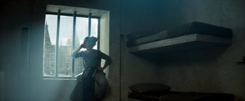 Movie still from “The Hitman's Bodyguard” (2017), directed by Patrick Hughes – A woman leaning against a window sill in a dark room; Wide shot, High angle