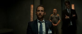 Movie still from “The Hitman's Bodyguard” (2017), directed by Patrick Hughes – A man in a suit and tie standing next to another man in a suit; Medium shot, Over the shoulder angle
