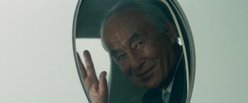 Movie still from “The Hitman's Bodyguard” (2017), directed by Patrick Hughes – An older man in a suit and tie looking out of a window; Close Up shot, Over the shoulder angle