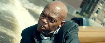 Movie still from “The Hitman's Bodyguard” (2017), directed by Patrick Hughes – An older bald man with a black jacket and a white shirt; Close Up shot, Low angle