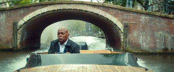 Movie still from “The Hitman's Bodyguard” (2017), directed by Patrick Hughes – A man sitting in a boat on a river; Wide shot, Over the shoulder angle