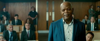 Movie still from “The Hitman's Bodyguard” (2017), directed by Patrick Hughes – An older man in a blue suit standing in a room; Medium shot, Low angle