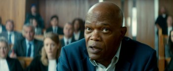 Movie still from “The Hitman's Bodyguard” (2017), directed by Patrick Hughes – A man in a suit and tie looking at the camera; Close Up shot, Over the shoulder angle