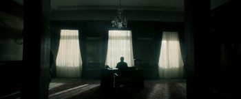 Movie still from “The Hitman's Bodyguard” (2017), directed by Patrick Hughes – A man sitting at a desk in front of a window; Extreme Wide shot, Low angle