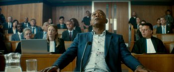 Movie still from “The Hitman's Bodyguard” (2017), directed by Patrick Hughes – A man in a courtroom with blood on his face; Medium shot, Low angle