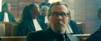 Movie still from “The Hitman's Bodyguard” (2017), directed by Patrick Hughes – An older man with glasses and a beard; Close Up shot, Over the shoulder angle