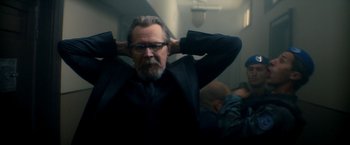 Movie still from “The Hitman's Bodyguard” (2017), directed by Patrick Hughes – A man with a beard and glasses in a black suit; Medium shot, Over the shoulder angle