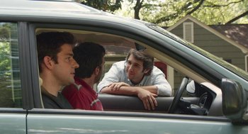 Movie still from “The Hollars” (2016), directed by John Krasinski – Three men sitting in the back seat of a car; Medium shot, Over the shoulder angle