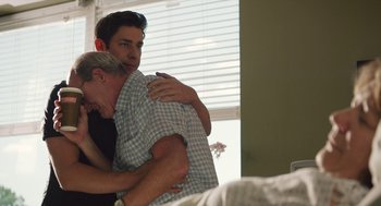Movie still from “The Hollars” (2016), directed by John Krasinski – Two men hugging each other in a bedroom; Medium shot, Over the shoulder angle