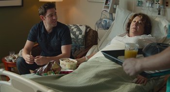 Movie still from “The Hollars” (2016), directed by John Krasinski – A man sitting in a bed with a tray of food in front of a woman; Medium shot, Over the shoulder angle