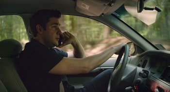 Movie still from “The Hollars” (2016), directed by John Krasinski – A man talking on a cell phone while sitting in the drivers seat of a car; Medium shot, High angle