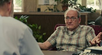 Movie still from “The Hollars” (2016), directed by John Krasinski – An older man sitting at a table in front of another man; Close Up shot, Over the shoulder angle