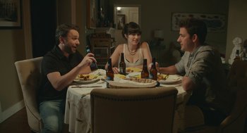 Movie still from “The Hollars” (2016), directed by John Krasinski – A group of people sitting around a table with food; Medium shot, High angle