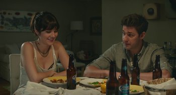 Movie still from “The Hollars” (2016), directed by John Krasinski – A man and a woman sitting at a dinner table with plates of food; Medium shot, Over the shoulder angle
