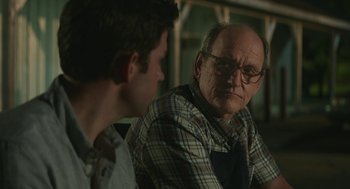 Movie still from “The Hollars” (2016), directed by John Krasinski – A man sitting next to another man in front of a window; Close Up shot, Over the shoulder angle