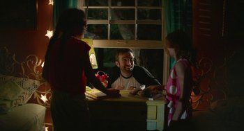 Movie still from “The Hollars” (2016), directed by John Krasinski – A man sitting at a table with two women; Medium shot, Over the shoulder angle