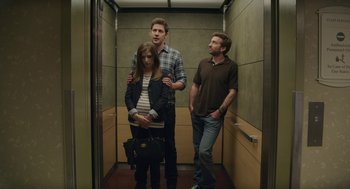 Movie still from “The Hollars” (2016), directed by John Krasinski – A group of people standing in an elevator; Medium shot, Over the shoulder angle