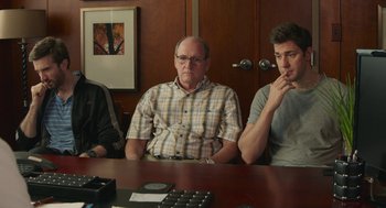 Movie still from “The Hollars” (2016), directed by John Krasinski – Three men sitting at a table in front of a door; Medium shot, Over the shoulder angle