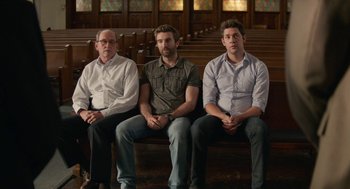 Movie still from “The Hollars” (2016), directed by John Krasinski – A group of men sitting on top of a wooden bench; Medium shot, Low angle