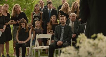 Movie still from “The Hollars” (2016), directed by John Krasinski – A group of people sitting on chairs in a field; Wide shot, Over the shoulder angle