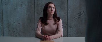 Movie still from “The Host” (2013), directed by Andrew Niccol – A woman sitting at a table with her hands clasped together; Medium shot, Over the shoulder angle