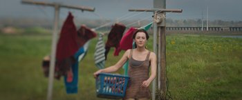Movie still from “The Host” (2013), directed by Andrew Niccol – A woman holding a laundry basket on a clothes line; Medium shot, Low angle