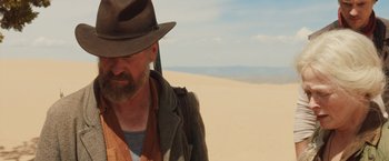 Movie still from “The Host” (2013), directed by Andrew Niccol – A man with a beard wearing a hat standing in the sand; Medium shot, Over the shoulder angle