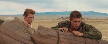 Movie still from “The Host” (2013), directed by Andrew Niccol – Two young men leaning on a rock in the desert; Medium shot, Over the shoulder angle
