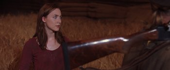 Movie still from “The Host” (2013), directed by Andrew Niccol – A woman holding a rifle in a barn; Medium shot, Over the shoulder angle