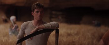 Movie still from “The Host” (2013), directed by Andrew Niccol – A young man leaning on a pole in a field; Medium shot, Over the shoulder angle