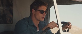 Movie still from “The Host” (2013), directed by Andrew Niccol – A young man driving a truck wearing sunglasses; Close Up shot, Low angle