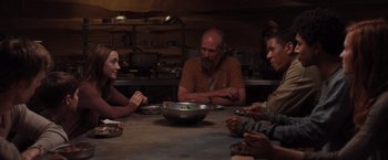 Movie still from “The Host” (2013), directed by Andrew Niccol – A group of people sitting at a table with a bowl of food on it; Medium shot, Over the shoulder angle