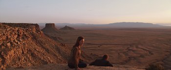 Movie still from “The Host” (2013), directed by Andrew Niccol – A woman sitting on top of a mountain next to a man; Extreme Wide shot, High angle