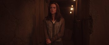 Movie still from “The Host” (2013), directed by Andrew Niccol – A woman standing in a dark hallway with lights; Medium shot, High angle