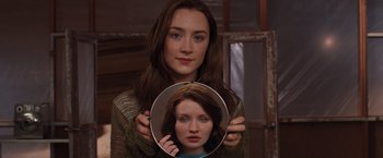 Movie still from “The Host” (2013), directed by Andrew Niccol – A woman is holding a round mirror in front of her face; Close Up shot, Over the shoulder angle